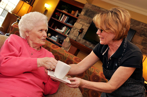 A caregiver serves a warm drink to an elderly woman, highlighting a moment of care and companionship.