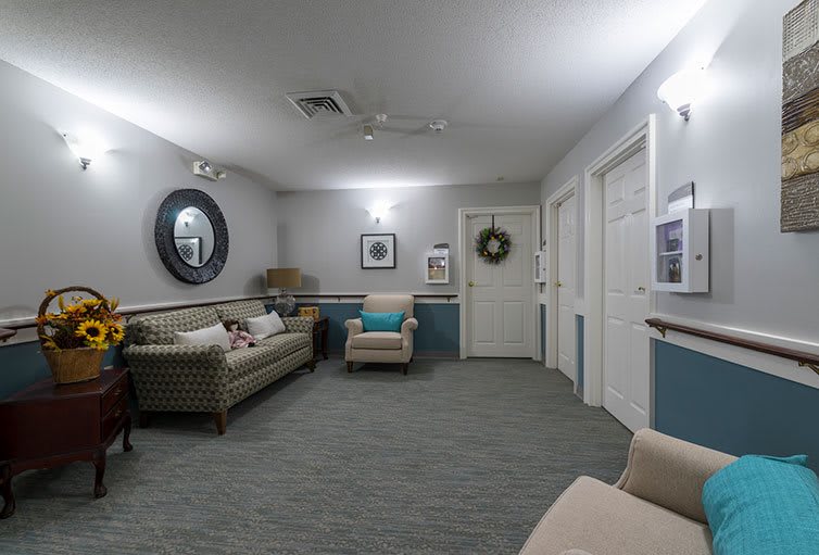 A cozy waiting room with sofas and armchairs, decorated with a mirror and wall art.