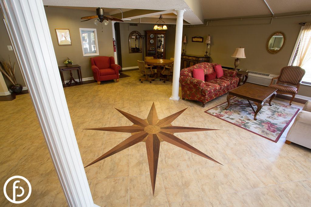A cozy living room features a unique compass rose design on the floor, with comfortable furniture and decorative columns.