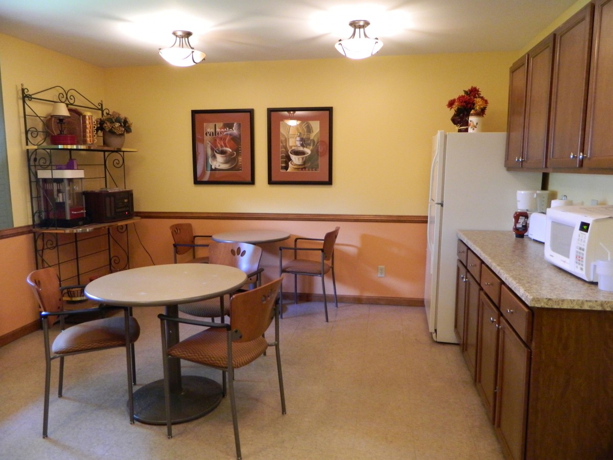 A cozy kitchen and dining area with wooden cabinets and round tables.