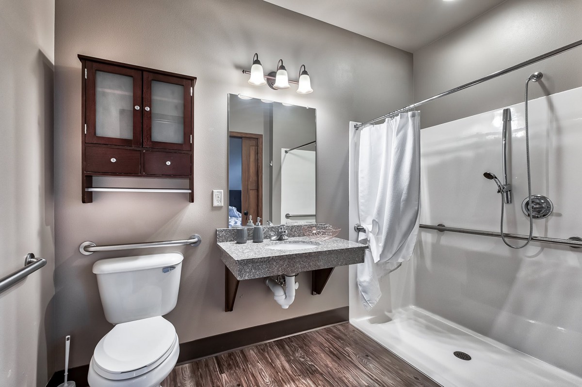 A modern bathroom with a shower, sink, and toilet.