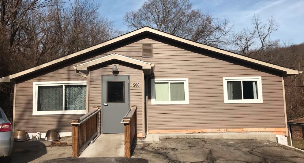 A small residential house with a ramp leading to the front door.