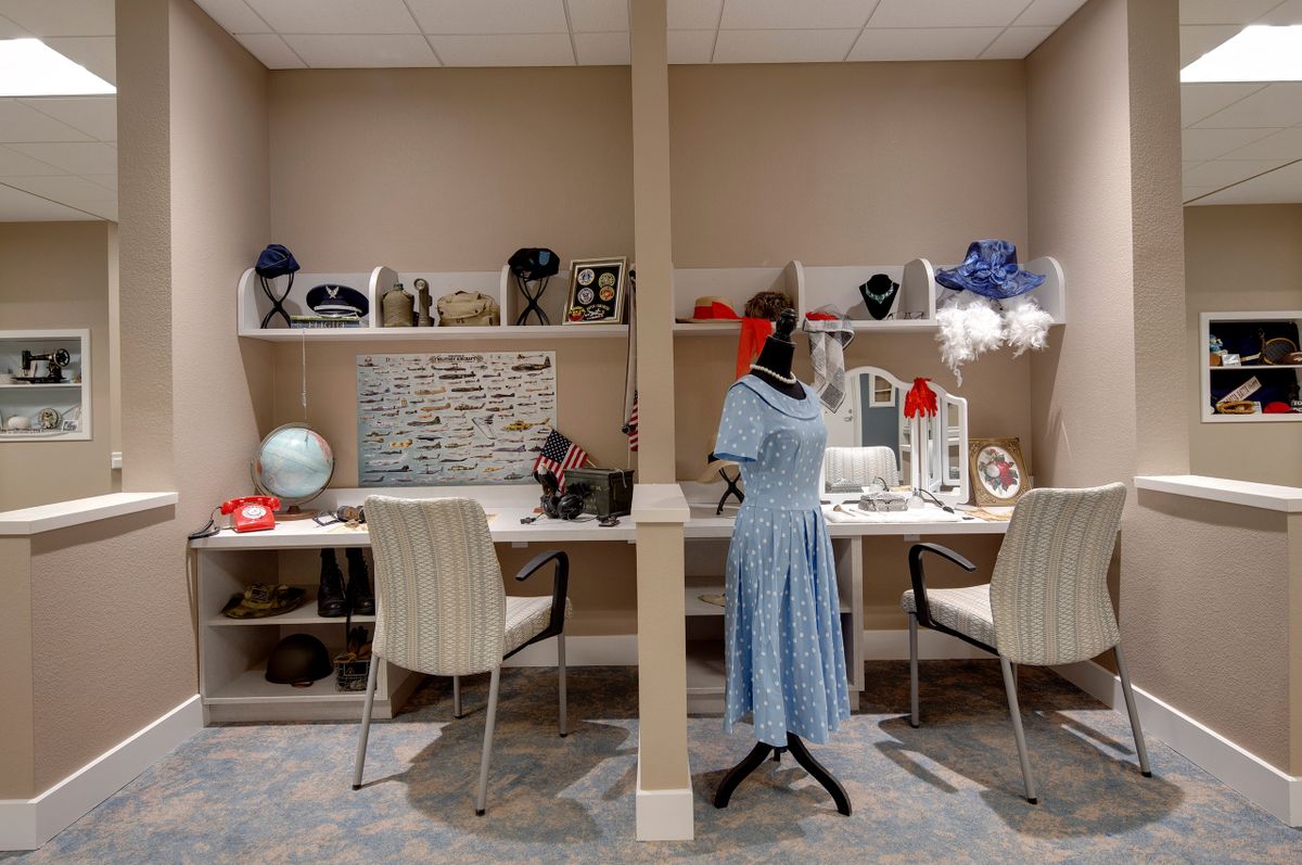 A cozy vintage dressing room features a mannequin in a retro dress, surrounded by various hats and accessories.