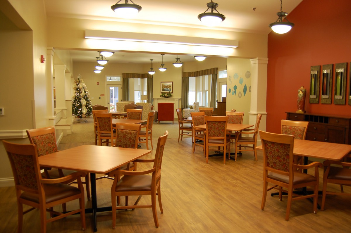 A spacious dining area with wooden tables and chairs, well-lit with elegant ceiling lights.