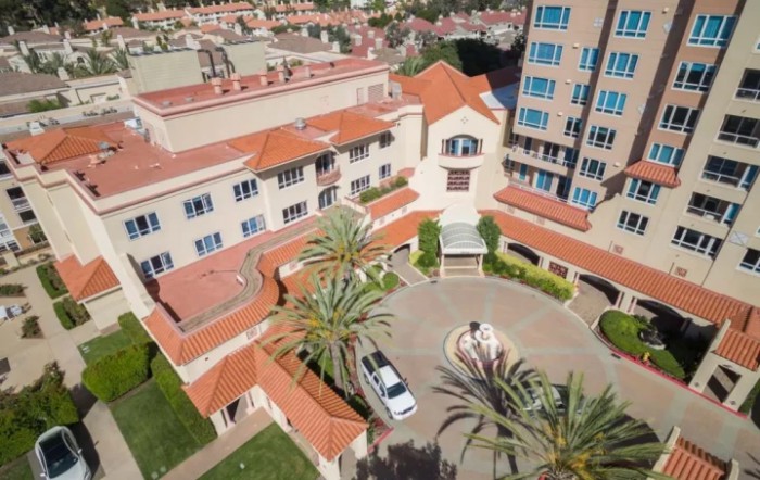 Aerial view of a hotel courtyard with palm trees and a parked vehicle.