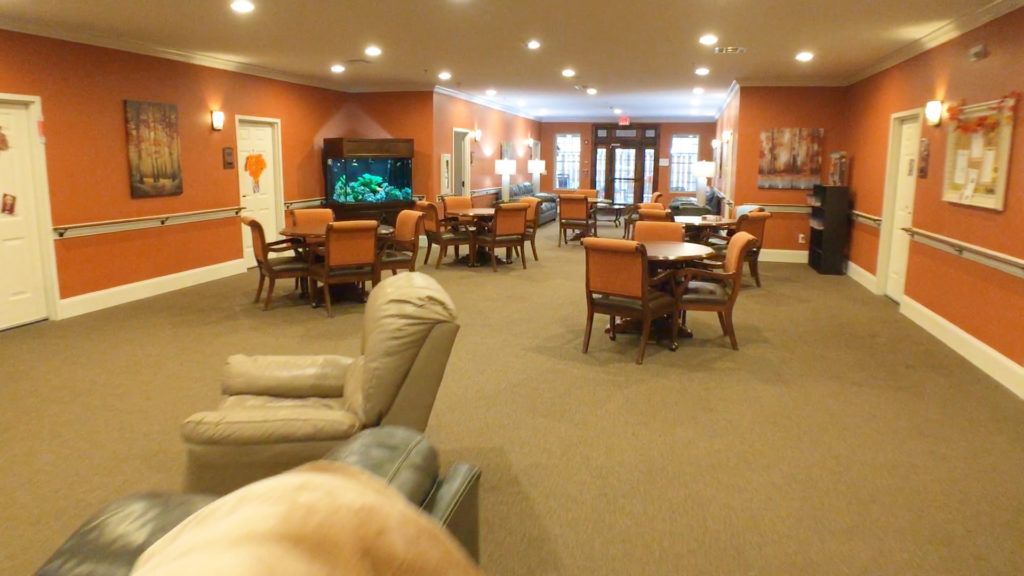 A cozy lounge area with multiple tables and chairs, a television, and warm lighting.
