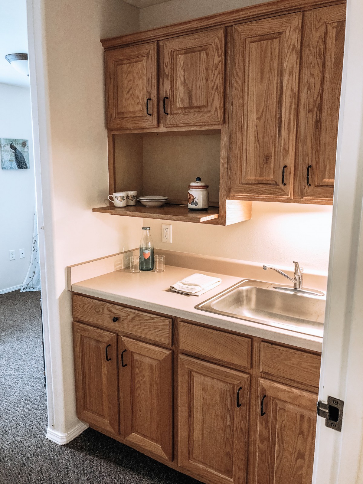 A small kitchen area with wooden cabinets and a stainless steel sink.