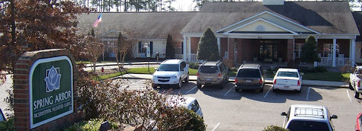 A view of a parking lot with various vehicles parked outside a building.