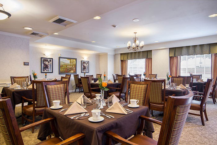 An elegantly set dining room with neatly arranged tables and chairs, ready for guests.