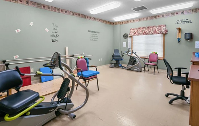 A rehabilitation room equipped with exercise machines and chairs for physical therapy.