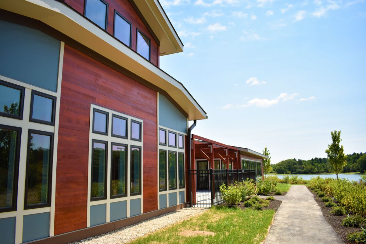 A modern house with wooden siding and large windows set in a landscaped outdoor area.