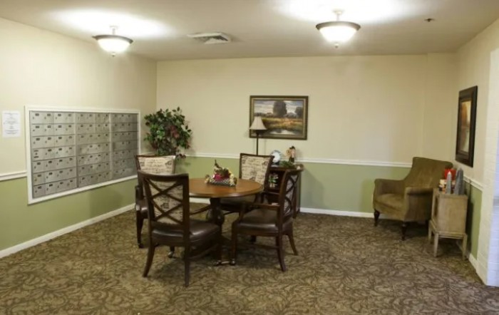 Cozy living room with a round table and chairs, decorated with a painting and lamp.