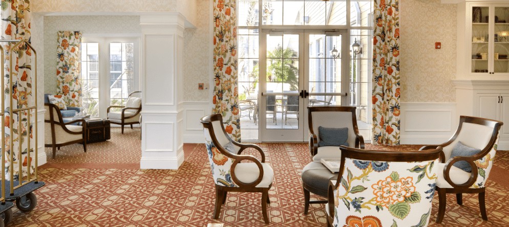 A cozy lobby area featuring elegant chairs, patterned wallpaper, and large windows letting in natural light.