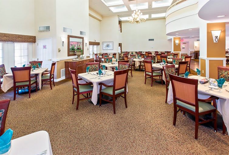A spacious dining area with neatly arranged tables and chairs, featuring a chandelier and elegant decor.