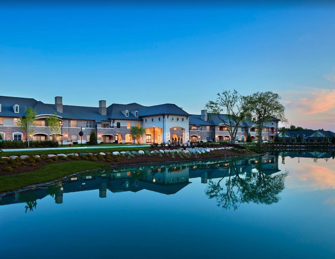 A luxurious mansion reflected in a tranquil lake at dusk.