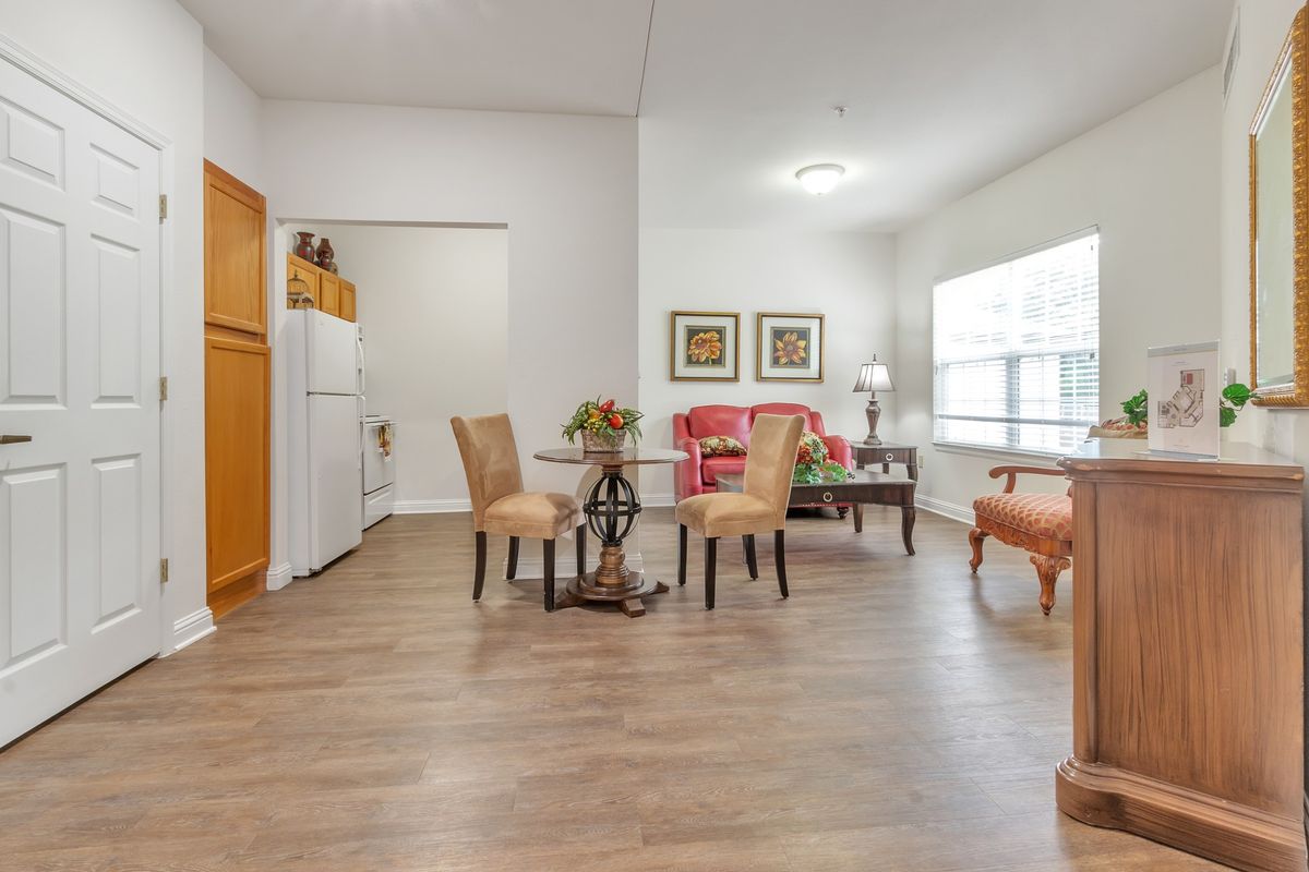 A bright and spacious living room with a dining area, featuring hardwood floors, stylish furniture, and large windows.