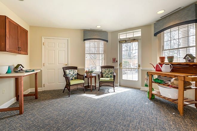 A bright and cozy interior space featuring chairs, a table, and shelves with natural light streaming in.