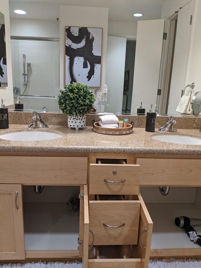 A well-organized bathroom vanity featuring double sinks, mirrors, and decorative elements.