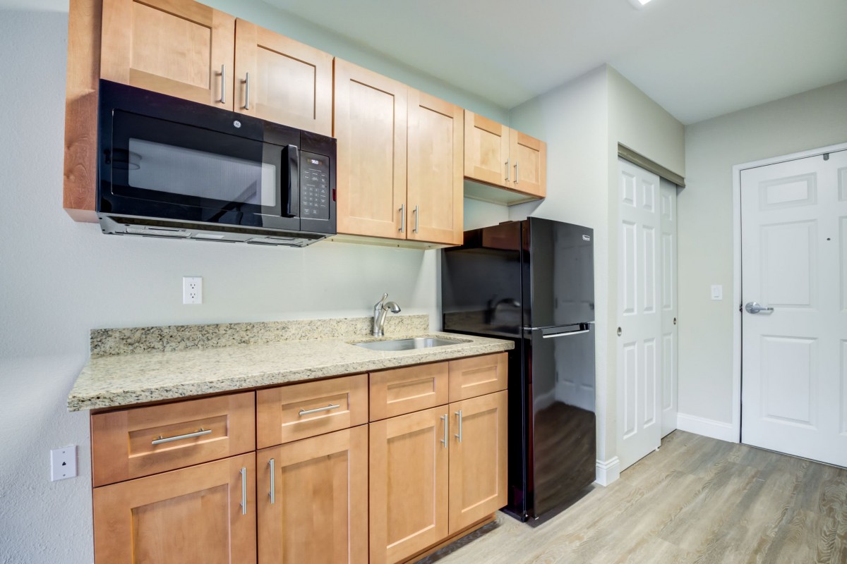 Modern kitchen with wooden cabinets, a microwave, and a small fridge.