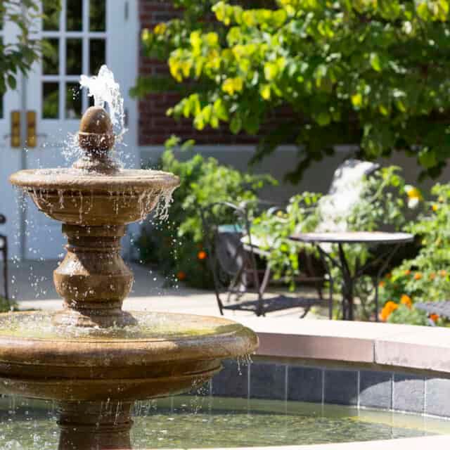 A beautiful garden with a flowing fountain on a sunny day.