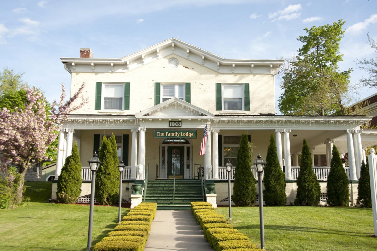 A charming two-story house with a spacious front porch and well-maintained lawn.