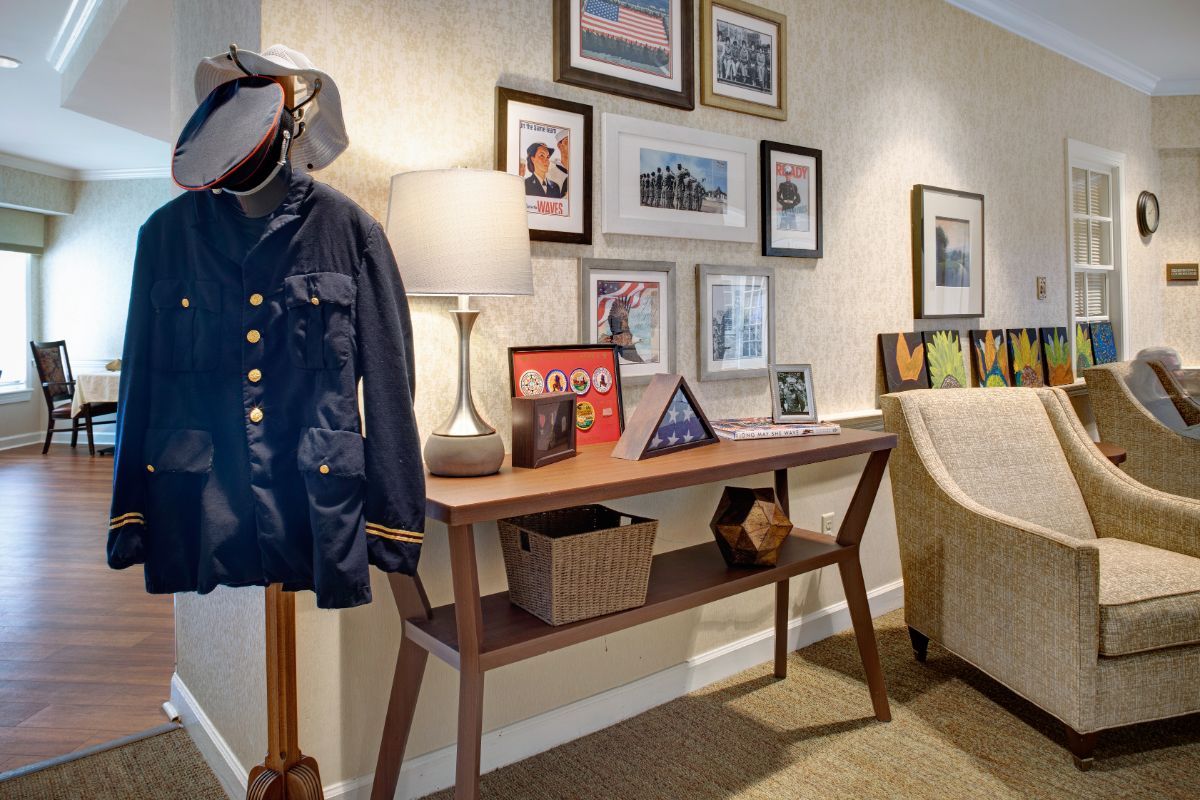 A cozy interior with a wooden console table, decorated with framed photos and a lamp, alongside a coat on a stand.