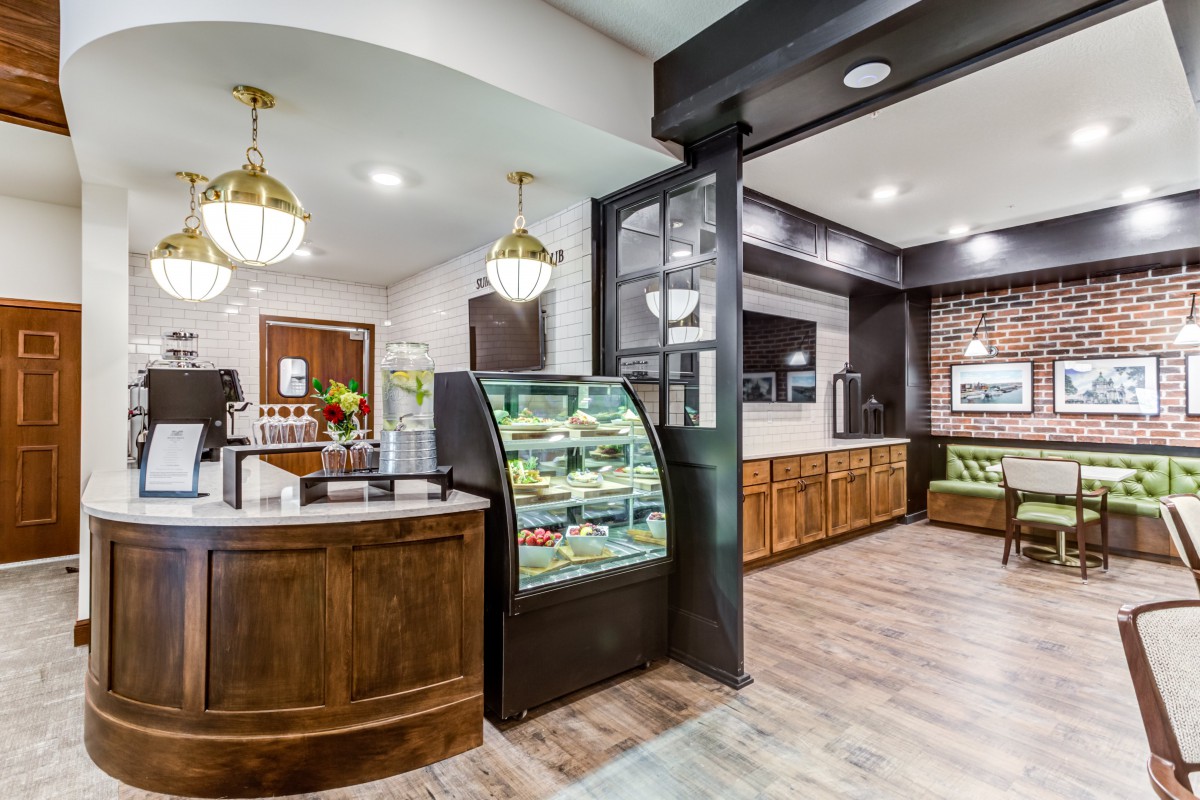 A modern cafe interior featuring a display case, wooden furnishings, and stylish lighting.