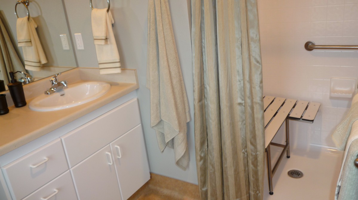 A bathroom featuring a sink with towels hanging nearby and a shower curtain.