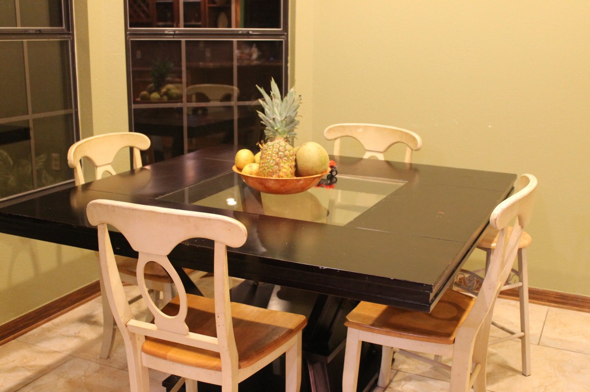 A dining area featuring a modern table with a fruit bowl centerpiece and chairs.