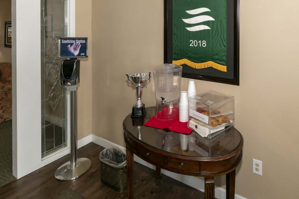 A small beverage and snack station with a trophy, cups, and framed artwork on display.