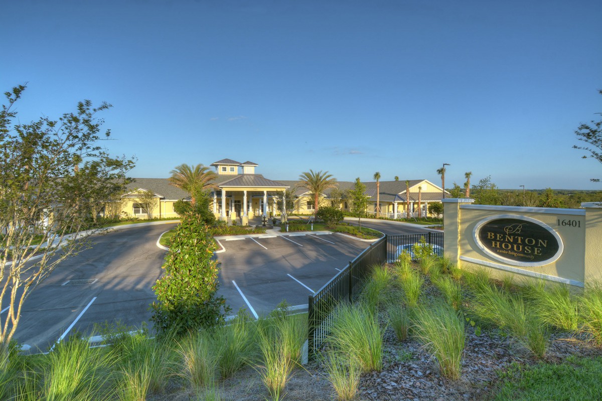 A beautifully landscaped entrance to a large building, surrounded by greenery and pathways.