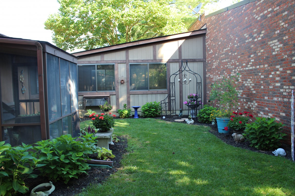 A well-maintained backyard garden with potted plants and a lush green lawn.