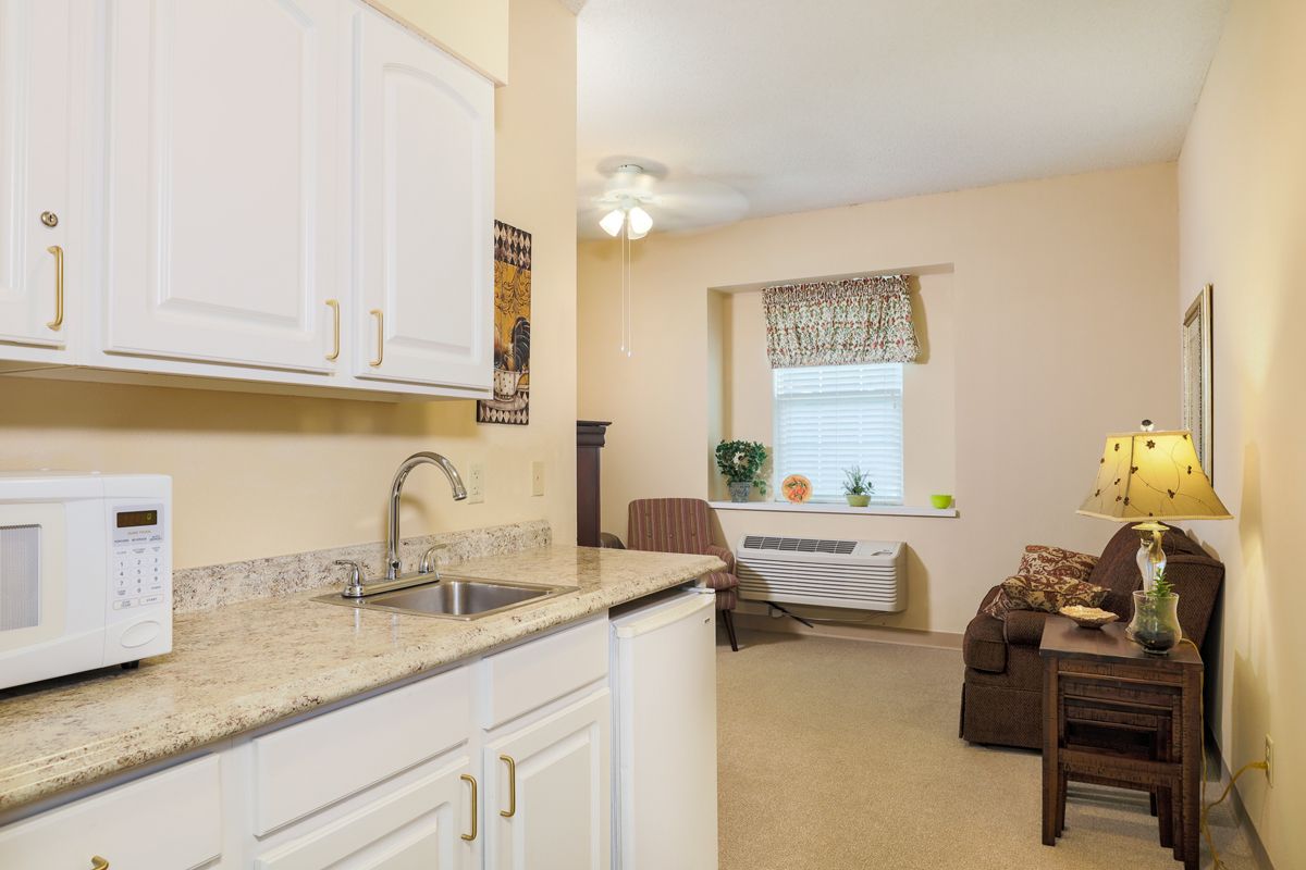 A cozy kitchen area leading into a comfortable living room with light-colored walls and modern furnishings.