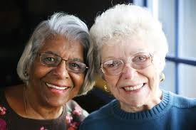 Two elderly women smiling and posing together, showcasing friendship.