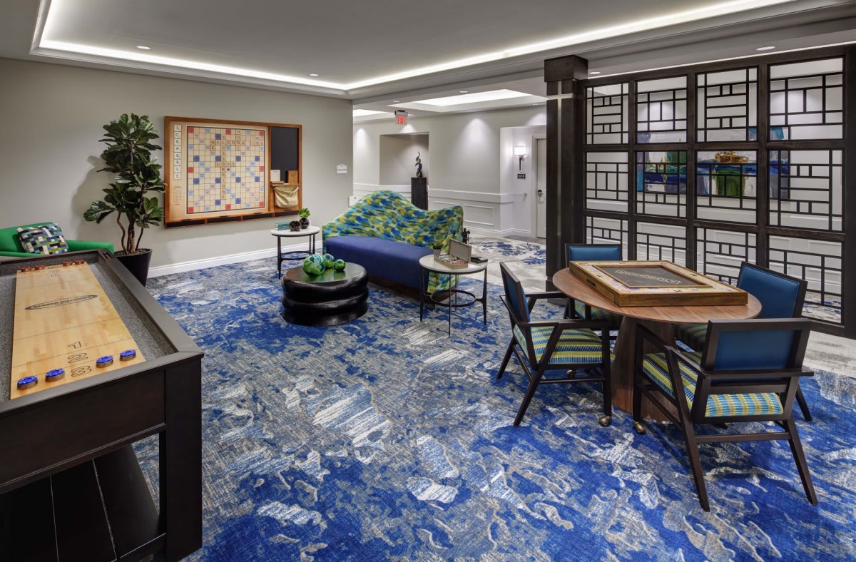 A modern lobby with stylish furniture and vibrant blue carpeting, featuring unique artwork on the walls.