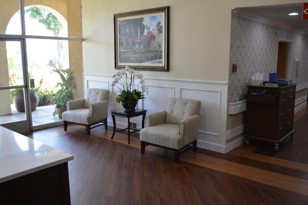A well-decorated waiting room with comfortable chairs, a painting on the wall, and plants for added ambiance.