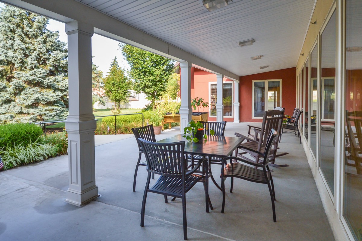 A cozy outdoor patio with a table and chairs, overlooking a landscaped garden.