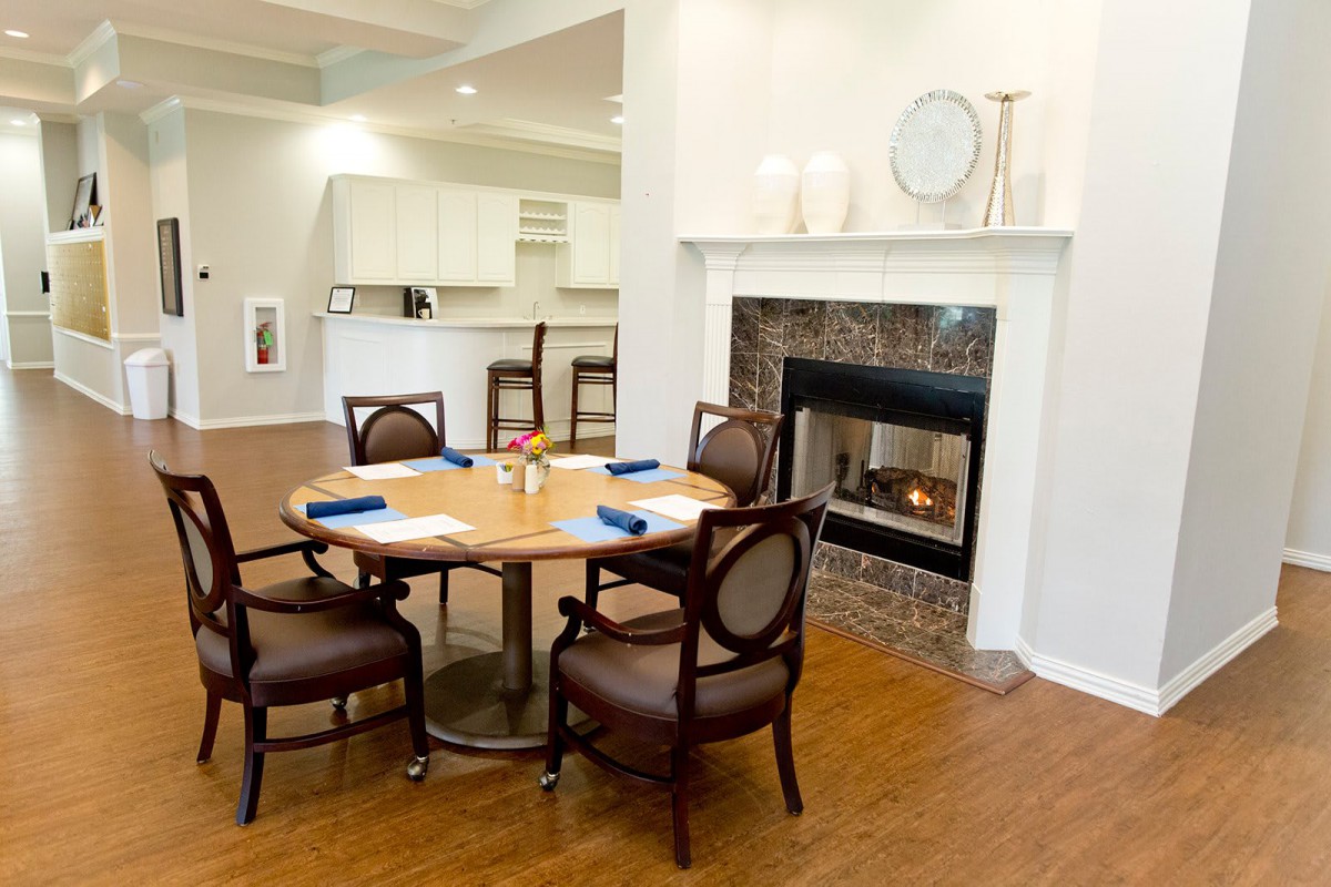 A cozy dining area featuring a round table with chairs and a fireplace.