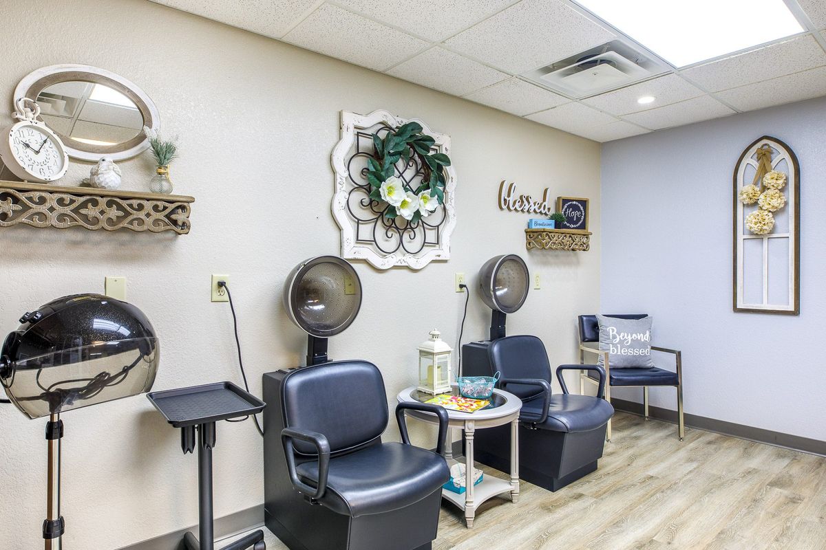 A cozy hair salon interior with chairs and hair dryers, complemented by decorative wall art.