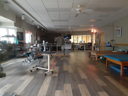 A spacious therapy room in a hospital, equipped with medical equipment and designed for rehabilitation.