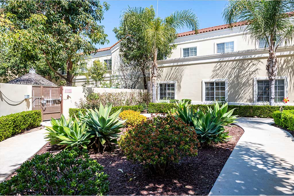 A well-maintained garden with lush greenery in front of a residential building.