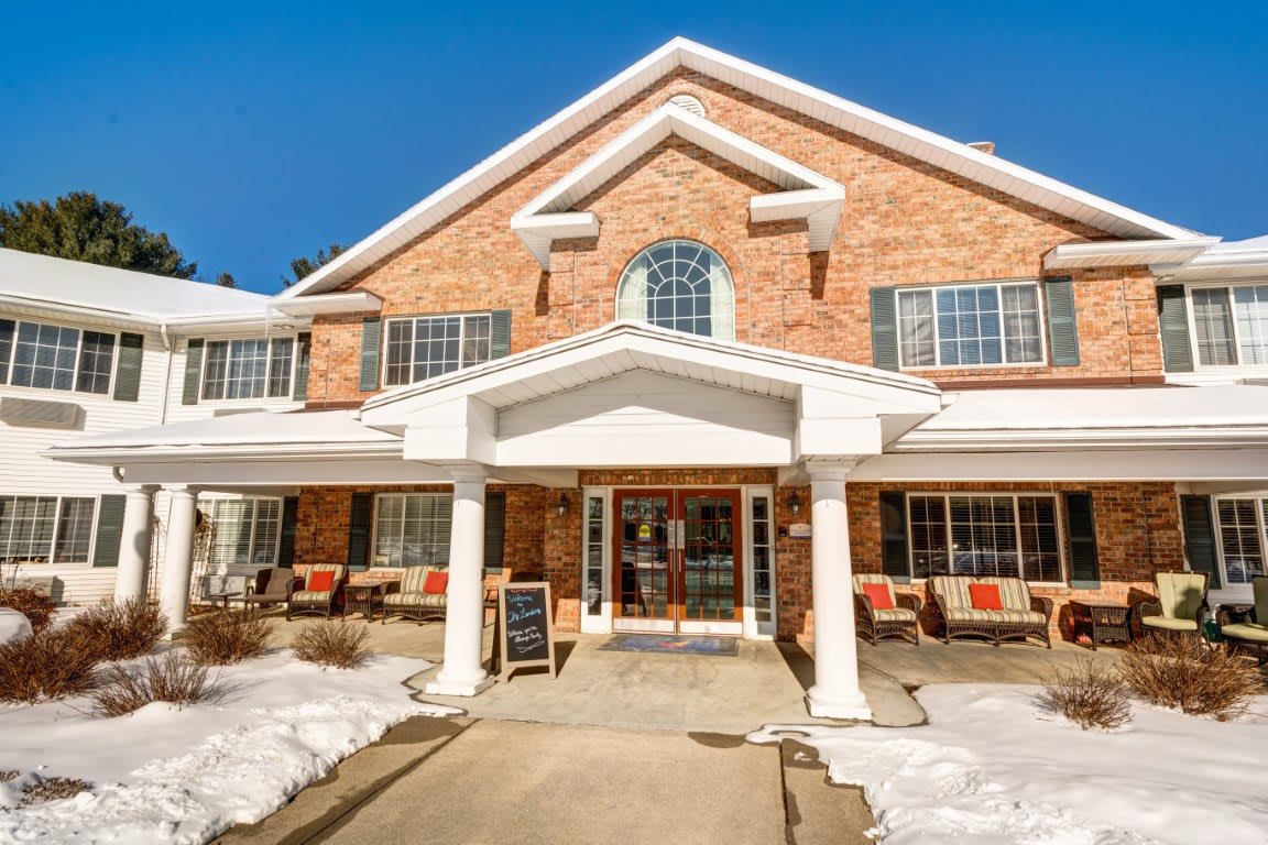 A two-story brick building with a front entrance, surrounded by snow on a clear winter day.
