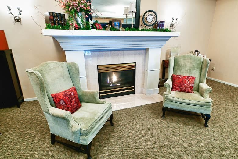 A cozy living room setting with a fireplace and two armchairs adorned with red cushions.