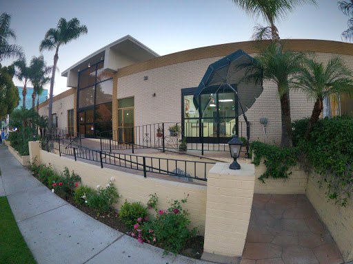 A modern residential building featuring a landscaped front yard and palm trees.