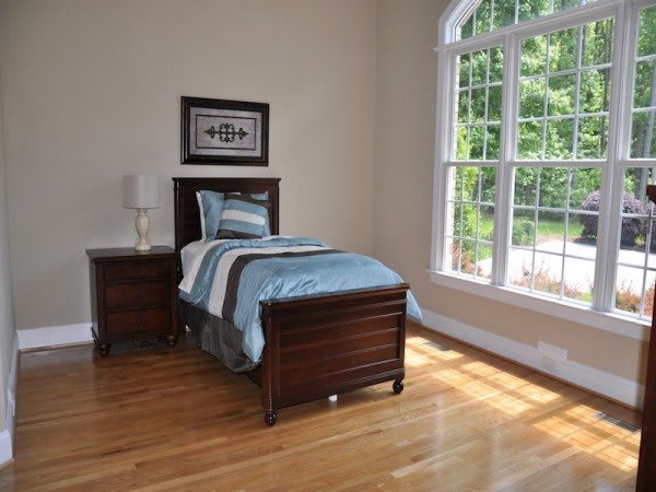 A minimalist bedroom with a single bed and large window allowing natural light.