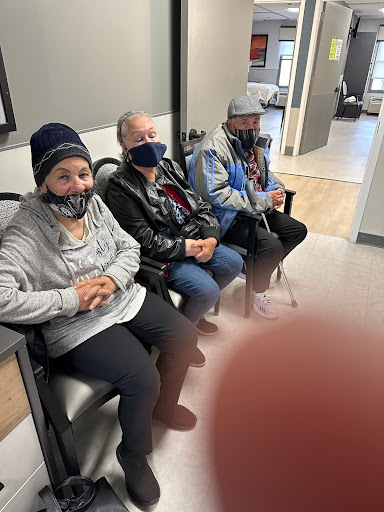 A group of people sitting together in a waiting area, all wearing masks.