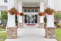 A symmetrical building entrance with columns and hanging potted plants.