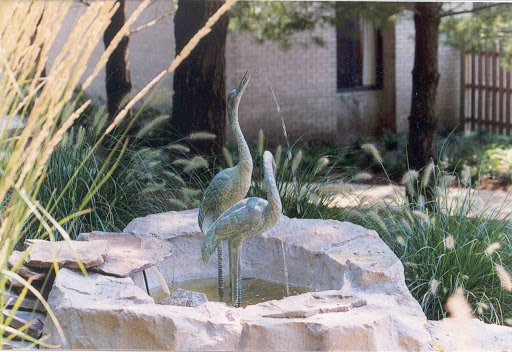 A beautiful sculpture of two birds standing gracefully in a serene garden fountain.