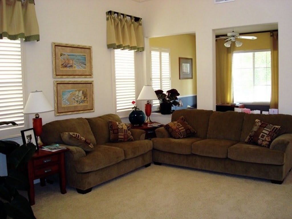 A cozy living room with a brown sectional sofa, decorative lamps, and framed artwork on the walls.