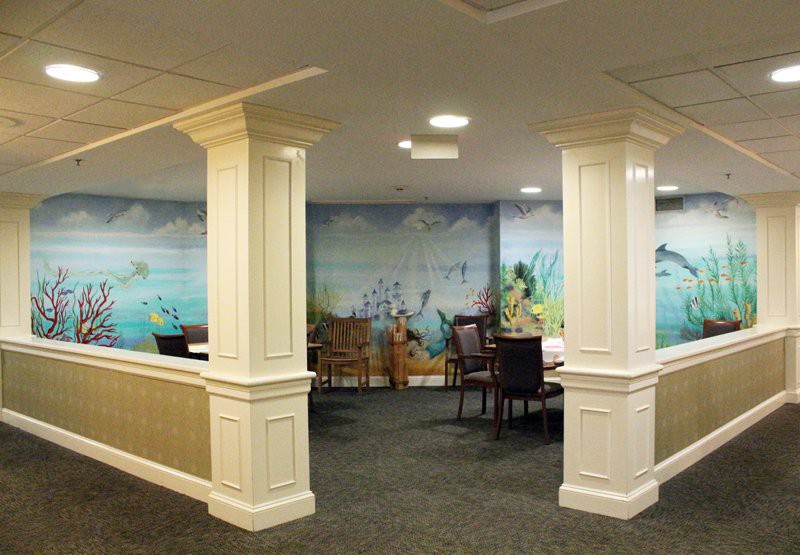 A cozy dining area featuring elegant columns, comfortable seating, and a scenic mural on the wall.